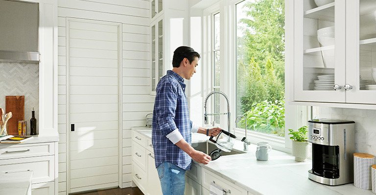 Man filling a coffee pot at kitchen sink